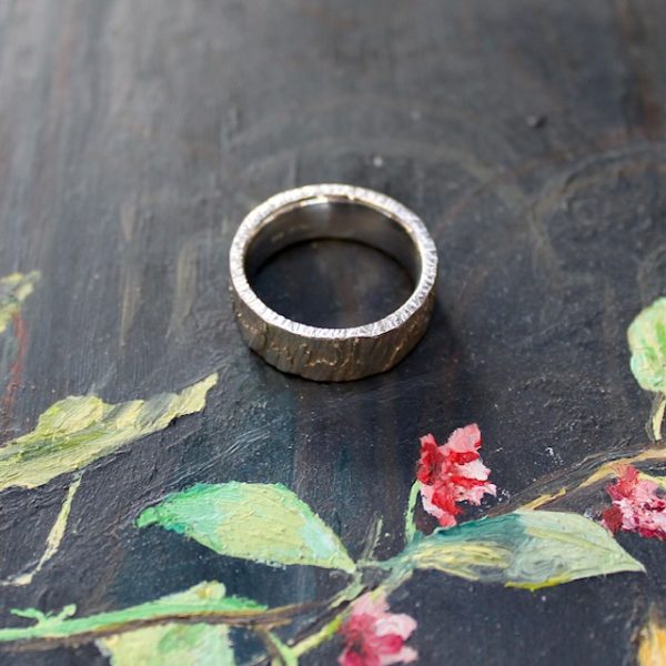 Marion Knorr Roh Ring, 8 mm breit und 2 mm hoch, aus Silber hell rhodiniert, wilde ehe ringe, die Oberfläche ist roh wie eine grob verputzte Wand, die Oberfläche gestalten Sie durch Ihr Tragen selber. Ring liegend.